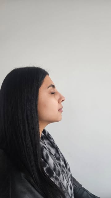 Perfil de una mujer de pelo largo y oscuro con la piel limpia, sobre fondo claro
